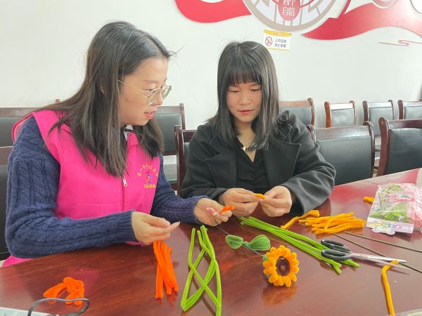 03051772710344679996.jpg 志愿者指导制作扭扭花束.JPG